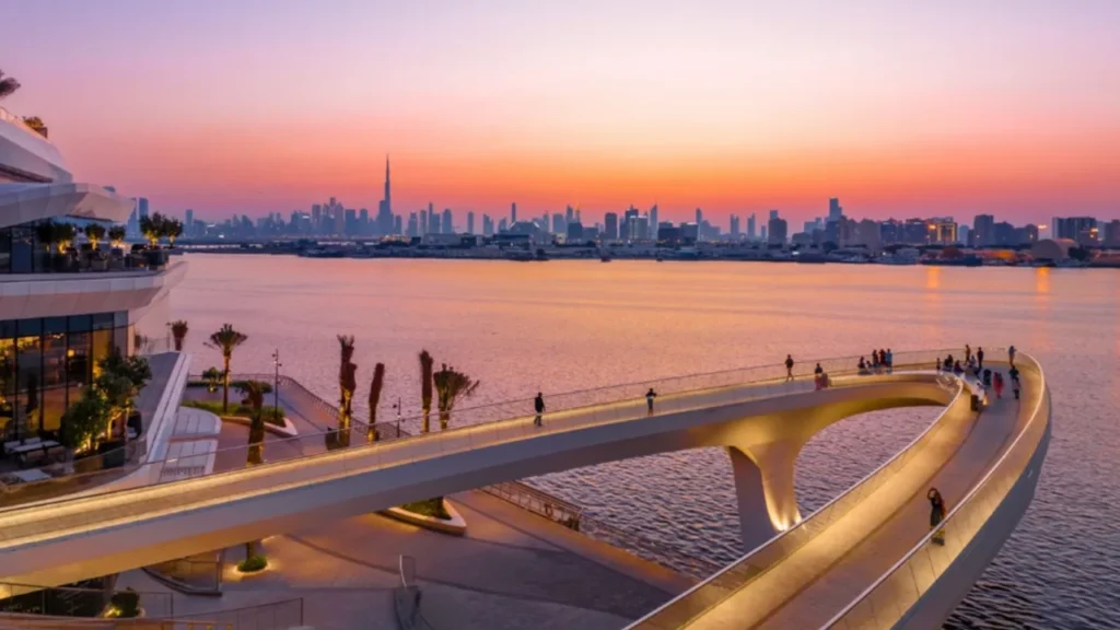 Sunset view over Dubai Creek Harbour promenade with Burj Khalifa skyline and waterfront bridge – presented by Tohid Fetrat.