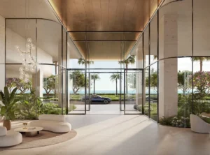 Interior view of the residential lobby at Alba Residences, Dorchester Collection by OMNIYAT, featuring a double height entrance, refined architectural details, soft lighting, lush indoor landscaping, and direct visual connection to the waterfront on Palm Jumeirah. Presented by Tohid Fetrat.