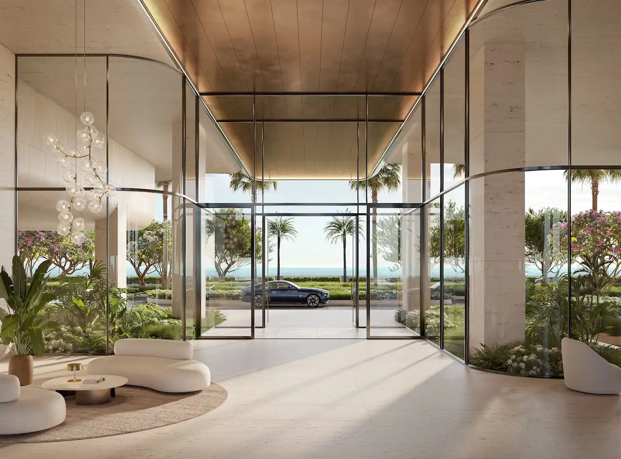 Interior view of the residential lobby at Alba Residences, Dorchester Collection by OMNIYAT, featuring a double height entrance, refined architectural details, soft lighting, lush indoor landscaping, and direct visual connection to the waterfront on Palm Jumeirah. Presented by Tohid Fetrat.