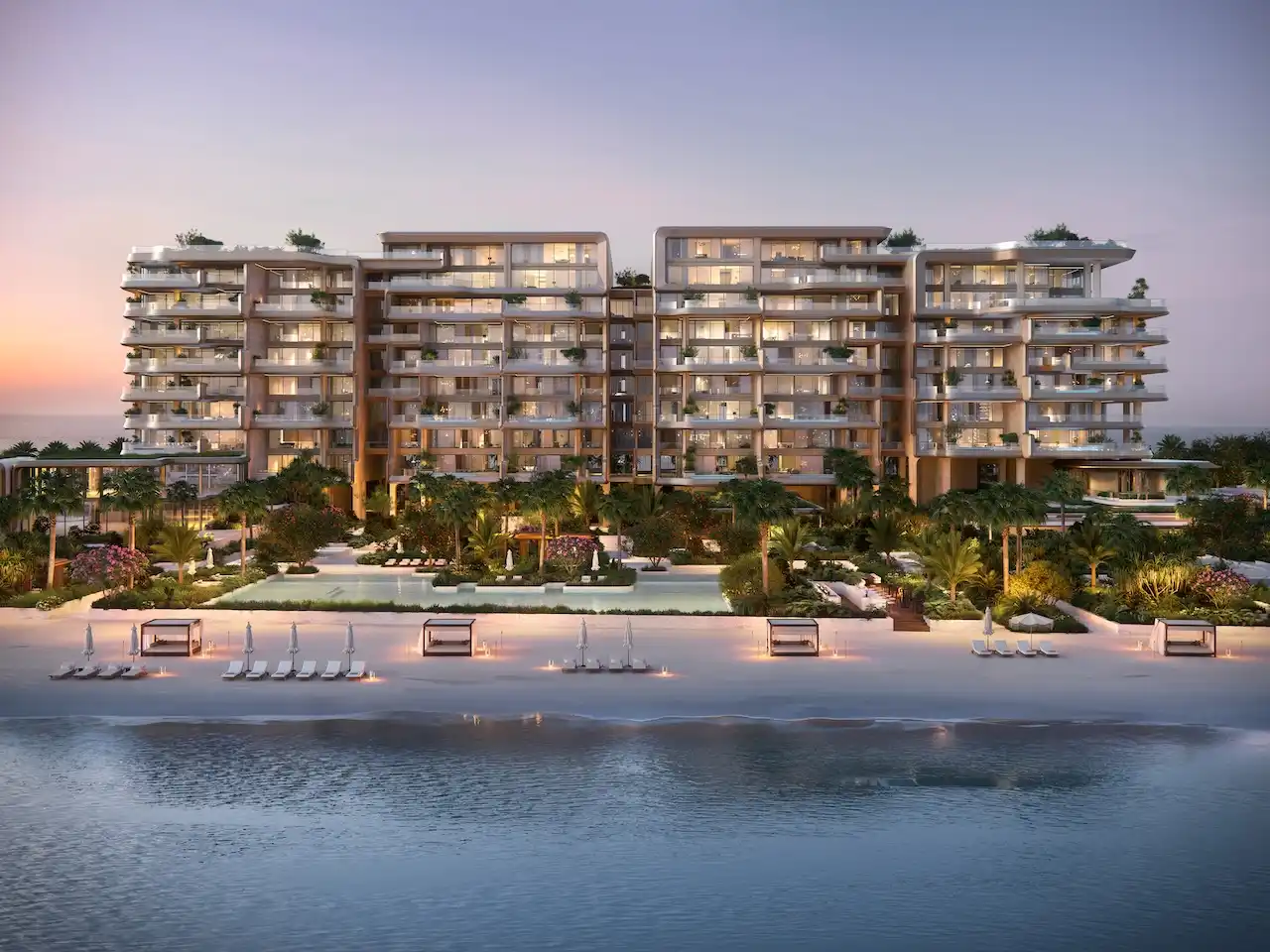 Evening beachfront elevation of Alba Residences, Dorchester Collection by OMNIYAT on Palm Jumeirah, highlighting warm architectural lighting, private beach loungers, landscaped gardens, and serene Gulf views. Presented by Tohid Fetrat.
