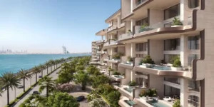 Roadside sea view of Alba Residences, Dorchester Collection by OMNIYAT on Palm Jumeirah, featuring sculpted balconies, private terraces, lush landscaping, and direct coastal frontage. Presented by Tohid Fetrat.