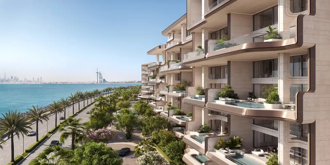 Roadside sea view of Alba Residences, Dorchester Collection by OMNIYAT on Palm Jumeirah, featuring sculpted balconies, private terraces, lush landscaping, and direct coastal frontage. Presented by Tohid Fetrat.