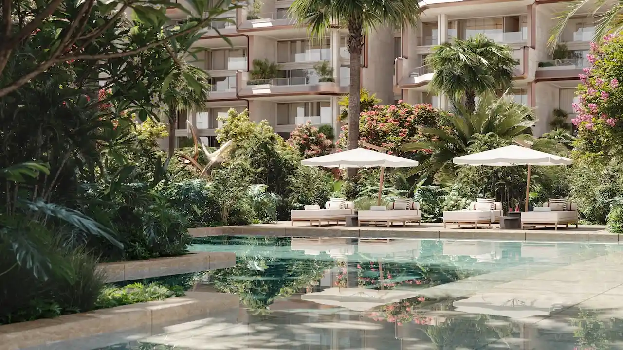 Tranquil garden swimming pool at Alba Residences, Dorchester Collection by OMNIYAT on Palm Jumeirah, surrounded by lush landscaping and luxury beachfront architecture. Presented by Tohid Fetrat.