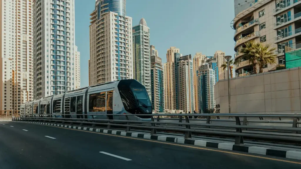 Dubai Tram passing through Dubai Marina with high-rise residential towers, showcasing modern urban mobility and efficient public transport infrastructure in Dubai. Presented by Tohid Fetrat.