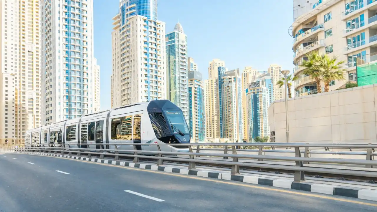 Dubai Tram traveling through Dubai Marina surrounded by modern high-rise residential towers, highlighting efficient urban transport and waterfront city living in Dubai. Presented by Tohid Fetrat.