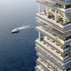 Aerial view of ENARA by OMNIYAT in Marasi Bay, Business Bay, showcasing stepped office terraces overlooking the water with a luxury yacht passing by. Presented by Tohid Fetrat.