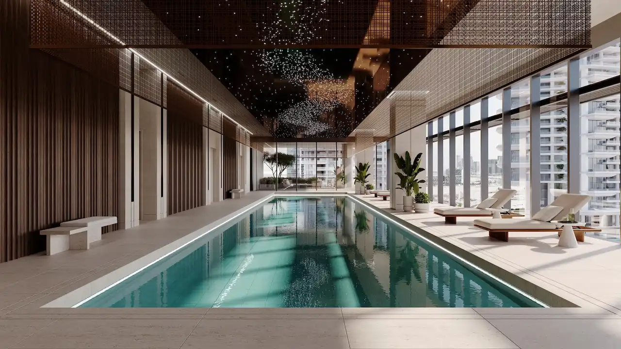 Members club indoor swimming pool at ENARA by OMNIYAT featuring a refined linear pool, lounge seating, floor to ceiling glazing, decorative ceiling panels, and Business Bay city views in Dubai. Presented by Tohid Fetrat.