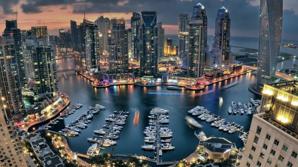Aerial sunset view of Dubai Marina with illuminated towers and waterfront skyline showcasing luxury urban living in Dubai presented by Tohid Fetrat.