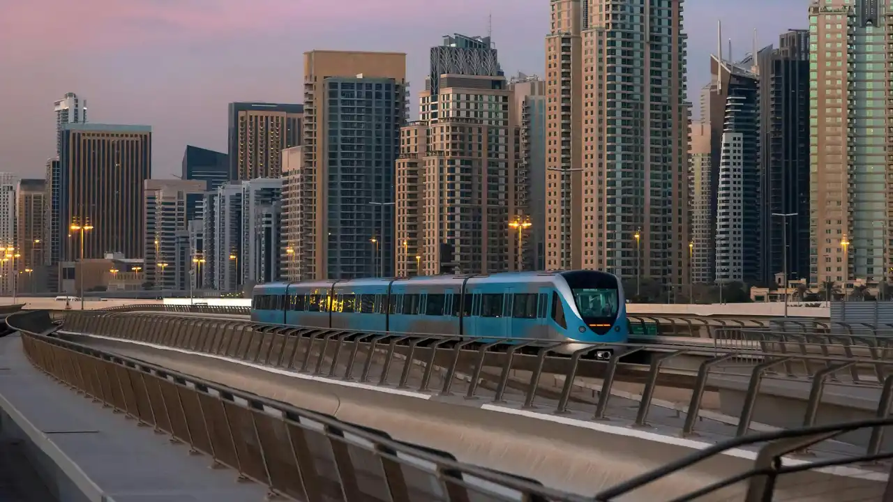 Dubai Metro Blue Line train operating on an elevated track with Dubai Marina skyline in the background, showcasing modern public transport infrastructure and urban connectivity, presented by Tohid Fetrat.