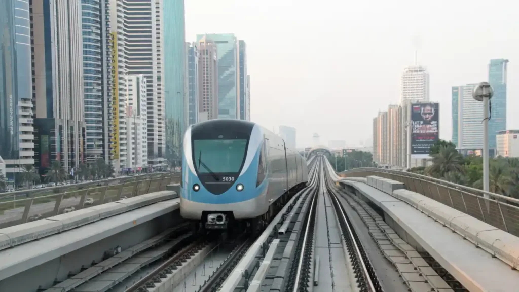 Dubai Metro Red Line train operating along Sheikh Zayed Road with surrounding high rise buildings, highlighting public transport connectivity across Dubai. Presented by Tohid Fetrat.