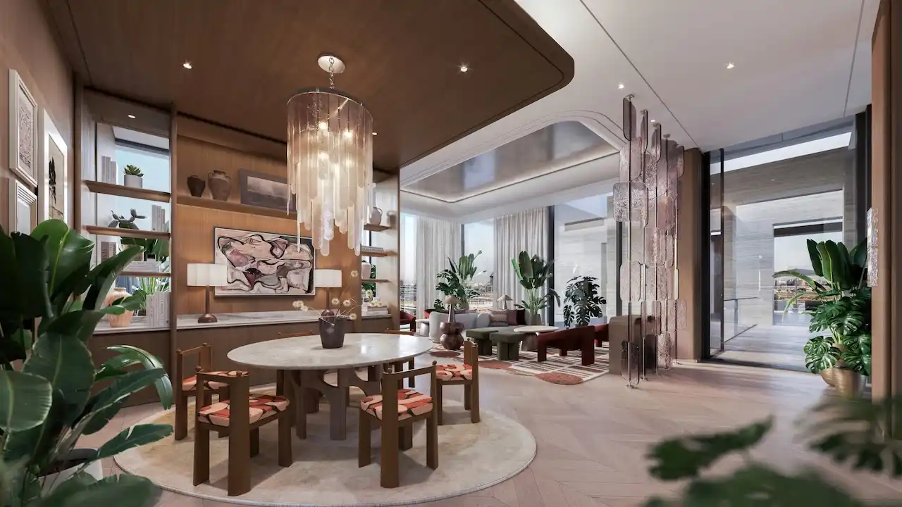 Luxury clubhouse lounge interior at Eltiera Views featuring elegant seating, warm wood finishes, designer lighting, and lush indoor greenery, creating a refined residential lifestyle in Dubai. Presented by Tohid Fetrat.