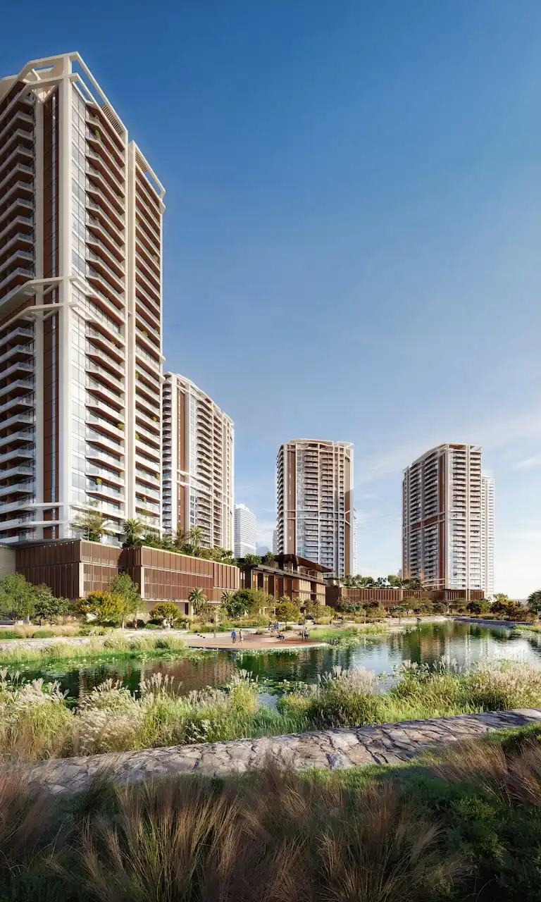 Exterior view of Eltiera Views showcasing modern residential towers, landscaped greenery, and a tranquil lagoon-style water feature in Dubai. Presented by Tohid Fetrat.