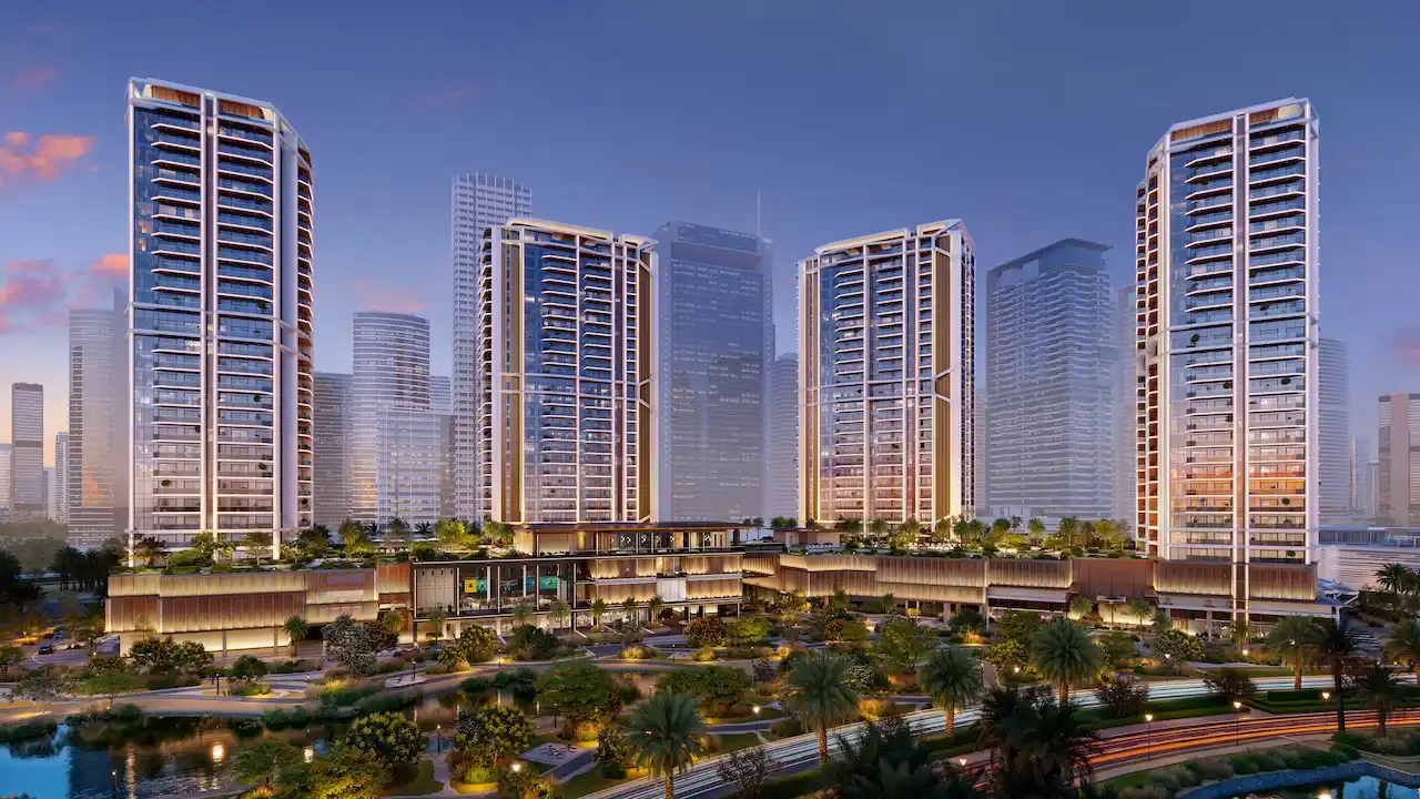 Night hero view of Eltiera Views featuring four illuminated residential towers above a landscaped podium and waterfront setting in Dubai. Presented by Tohid Fetrat.