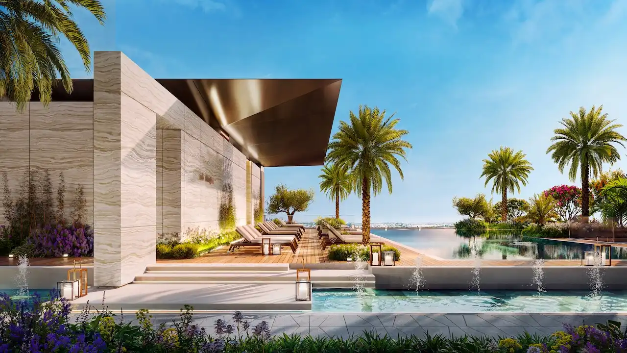 Luxury pool deck at Eltiera Views featuring sun loungers, palm trees, and landscaped surroundings, offering a resort-style residential experience in Dubai. Presented by Tohid Fetrat.