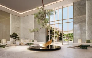 Elegant lobby entrance at Hado Tower in the SIORA community by Beyond featuring a sculptural water installation marble finishes natural light and serene landscaping presented by Tohid Fetrat.