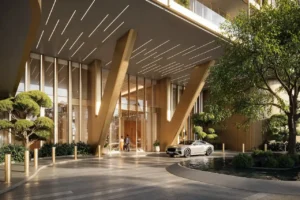 Primary drop off area of Hado Tower in the SIORA community by Beyond featuring grand golden structural columns floor to ceiling glass an elegant arrival driveway landscaped trees and a luxury car presented by Tohid Fetrat.