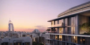 Exterior sunset view of MJL Nourelle in Madinat Jumeirah Living Dubai, showcasing elegant contemporary architecture with illuminated balconies and Burj Al Arab views, set within a low rise community near the Gulf. Presented by Tohid Fetrat.