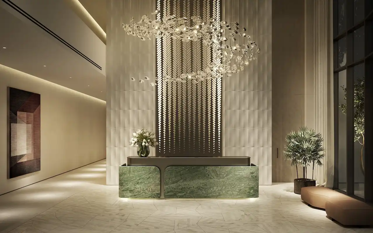 Dubai Madinat Jumeirah Living icindeki MJL Nourelle resepsiyon ve concierge bankosu; heykelsi avize, dokulu duvar tasarimi, dogal tas kaplamalar ve prestijli konut giris deneyimi sunar. Tohid Fetrat tarafindan sunulmustur.