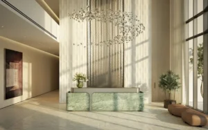 Reception area and main lobby at MJL Nourelle in Madinat Jumeirah Living Dubai, featuring double height ceilings, sculptural chandelier, refined stone finishes and a luxury residential welcome space. Presented by Tohid Fetrat.