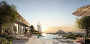 Rooftop infinity pool at MJL Nourelle in Madinat Jumeirah Living Dubai, featuring luxury sun loungers, landscaped terraces and direct views toward Burj Al Arab and the Gulf at sunset. Presented by Tohid Fetrat.