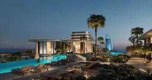 Rooftop infinity pool at MJL Nourelle in Madinat Jumeirah Living Dubai, featuring luxury loungers, landscaped terraces, evening ambiance and panoramic views toward Burj Al Arab and the Gulf. Presented by Tohid Fetrat.