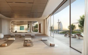 Wellness and yoga studio view at MJL Nourelle in Madinat Jumeirah Living Dubai, featuring a serene interior with natural wood finishes, floor to ceiling glass, outdoor terrace access and Burj Al Arab views near the Gulf. Presented by Tohid Fetrat.