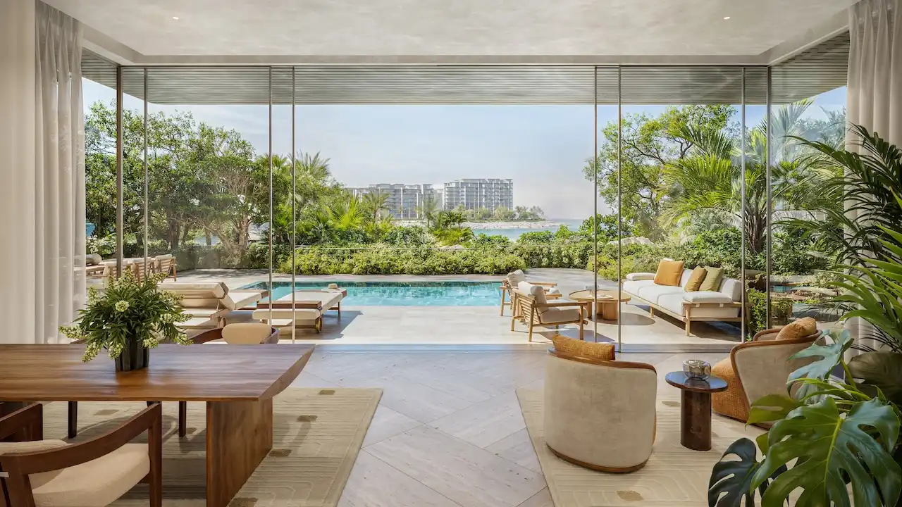Private garden and pool area of a 3 bedroom residence at Solaya by Meraas in Dubai, featuring floor to ceiling glass, outdoor lounge seating, landscaped greenery and seamless indoor outdoor living. Presented by Tohid Fetrat.