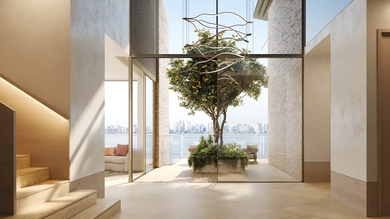 Entrance lobby of a 4 bedroom duplex at Solaya by Meraas in Dubai, featuring double height ceilings, floor to ceiling glass, a central indoor tree courtyard, natural light and refined contemporary architecture. Presented by Tohid Fetrat.