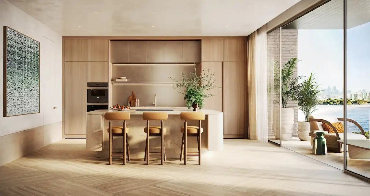 Luxury 4 bedroom apartment kitchen at Solaya by Meraas in Dubai, featuring a contemporary open plan layout, natural wood finishes, stone island, integrated appliances and seamless connection to a private terrace with waterfront views. Presented by Tohid Fetrat.