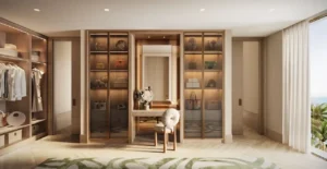 Luxury walk in wardrobe of a 4 bedroom apartment at Solaya by Meraas in Dubai, featuring bespoke wooden cabinetry, illuminated display shelves, private vanity area and refined finishes with a calm waterfront atmosphere. Presented by Tohid Fetrat.