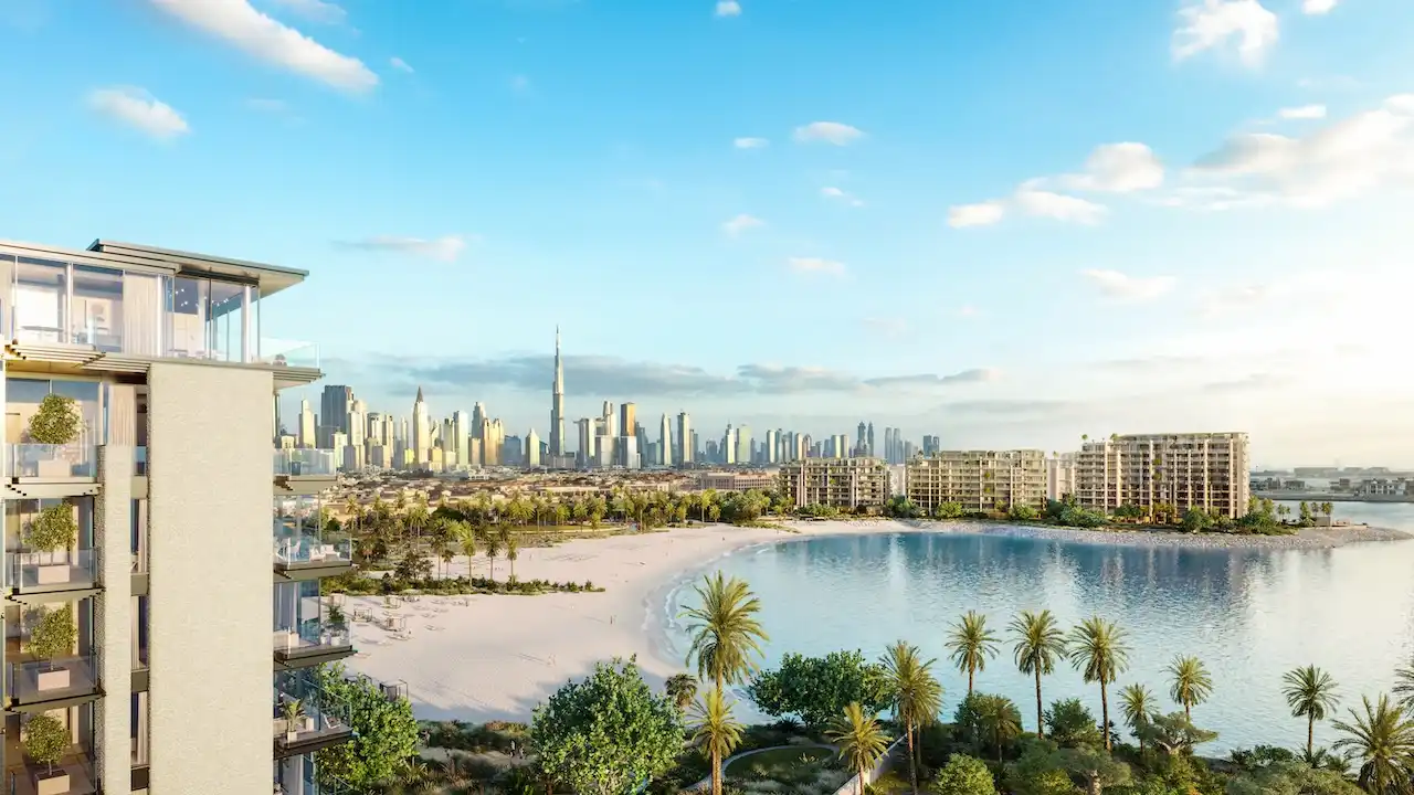 Panoramic lagoon and beach view of Solaya by Meraas in Dubai, showcasing low rise waterfront residences, palm lined shoreline and the Dubai skyline with Burj Khalifa in the background. Presented by Tohid Fetrat.
