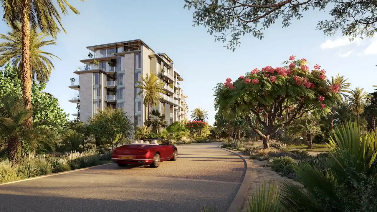 Landscaped access road view of Solaya by Meraas in Dubai, featuring low rise residential buildings surrounded by lush greenery, palm trees and a tranquil resort style environment. Presented by Tohid Fetrat.