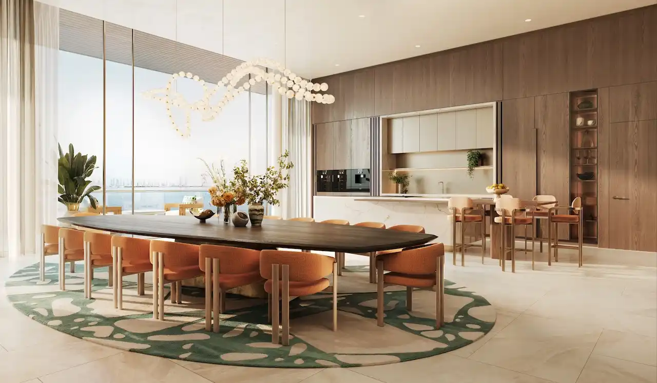 Penthouse dining and kitchen interior at Solaya by Meraas in Dubai, featuring a spacious dining table, open plan kitchen, floor to ceiling windows, refined wood finishes and panoramic waterfront views. Presented by Tohid Fetrat.