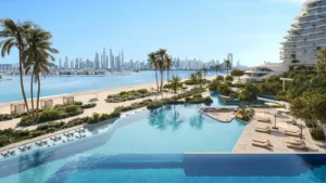 Infinity pool and private beachfront at Arival Piazza Passo by Beyond featuring expansive water edge design, sun loungers, landscaped palm gardens, direct beach access, and open sea views creating a resort style residential environment in Dubai. Presented by Tohid Fetrat.