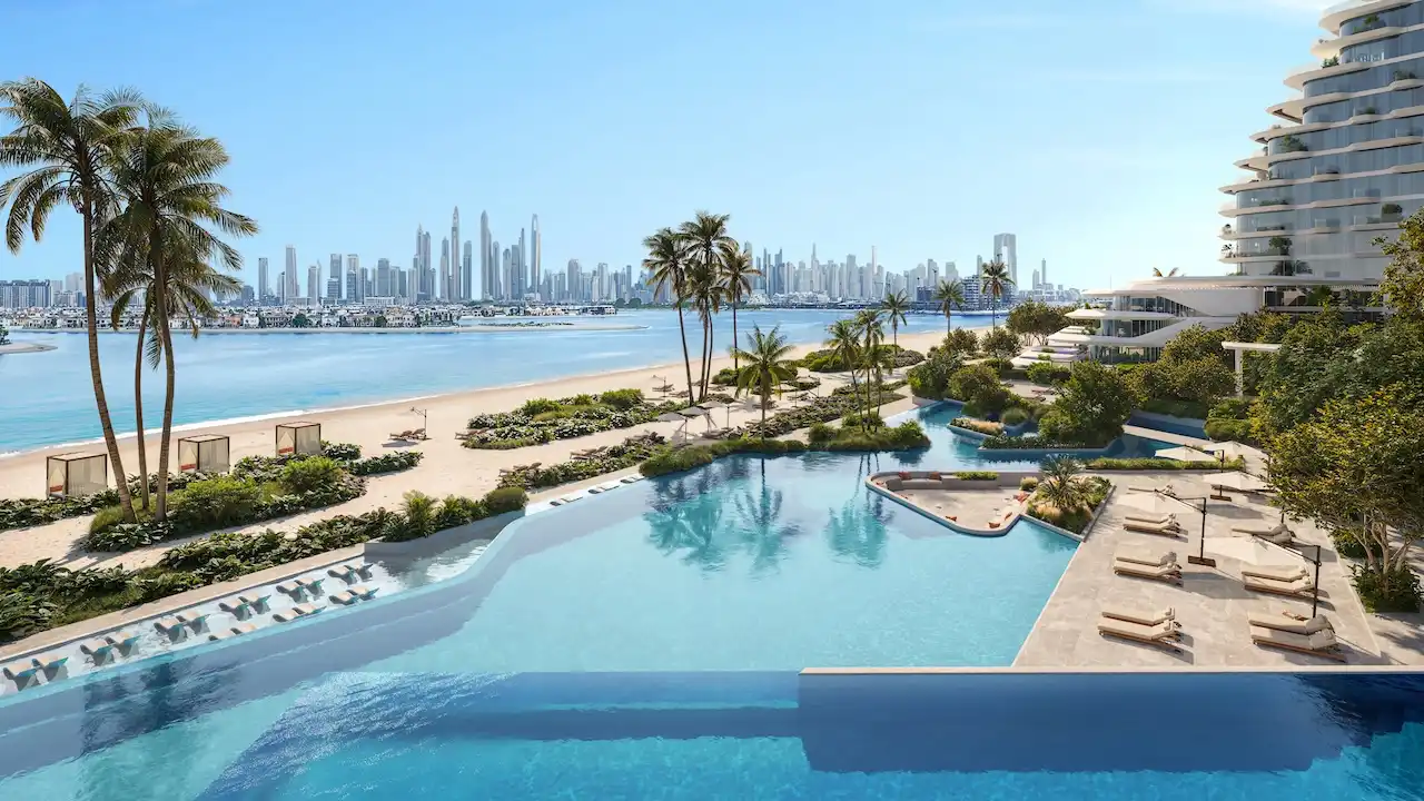 Infinity pool and private beachfront at Arival Piazza Passo by Beyond featuring expansive water edge design, sun loungers, landscaped palm gardens, direct beach access, and open sea views creating a resort style residential environment in Dubai. Presented by Tohid Fetrat.