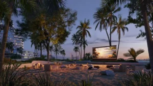 Outdoor cinema at Arival Piazza Passo by Beyond featuring a beachfront open air screening area with soft seating on sand, palm trees, landscaped surroundings, and evening ambiance designed for relaxed community gatherings. Presented by Tohid Fetrat.