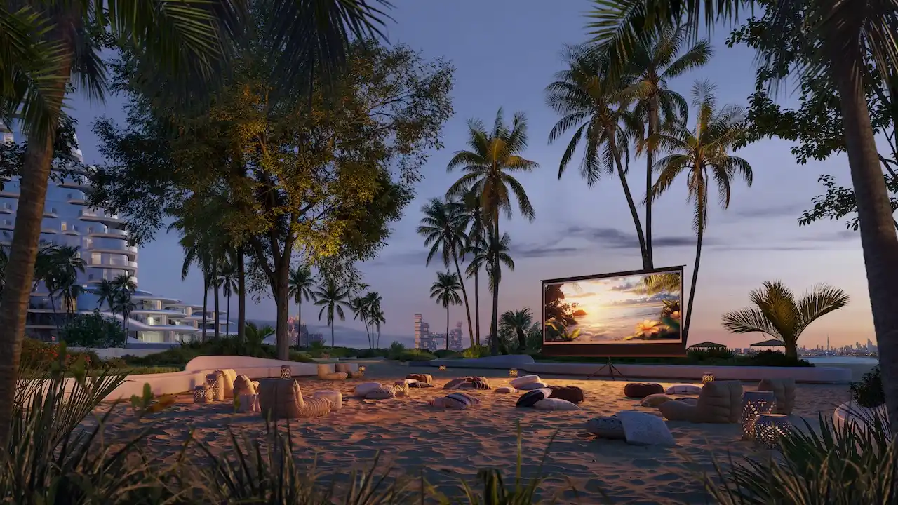 Outdoor cinema at Arival Piazza Passo by Beyond featuring a beachfront open air screening area with soft seating on sand, palm trees, landscaped surroundings, and evening ambiance designed for relaxed community gatherings. Presented by Tohid Fetrat.