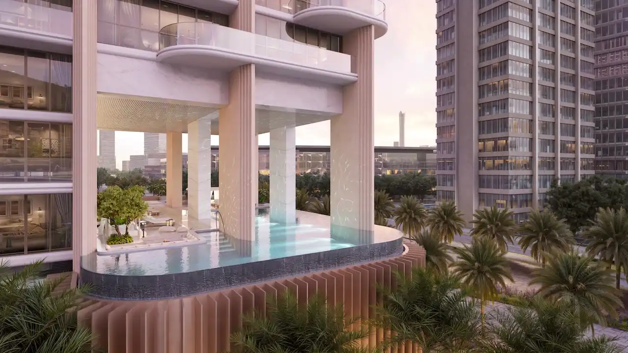 Elevated podium infinity pool at Atelis at d3, featuring sculptural columns, marble finishes, curved balconies, and lush landscaping within Dubai Design District. Presented by Tohid Fetrat.