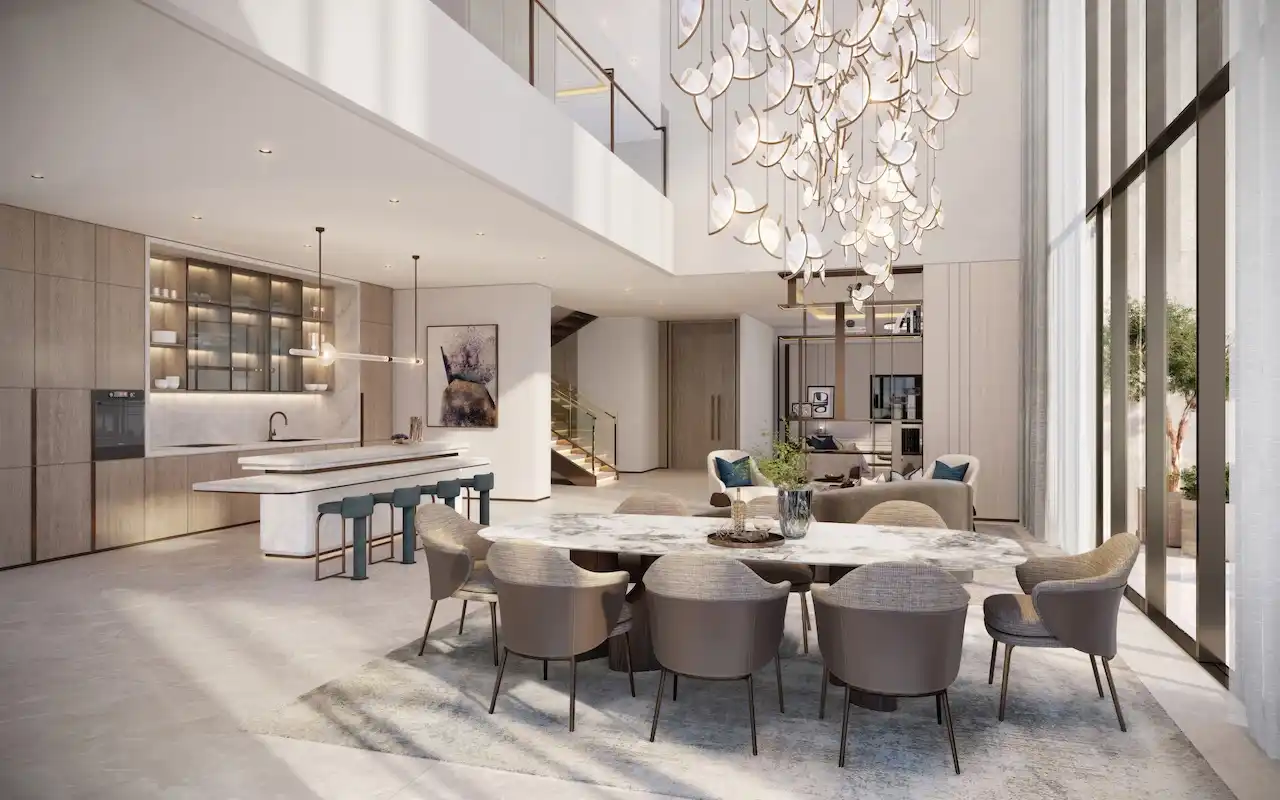 Double-height penthouse dining area at Atelis at d3 featuring a sculptural chandelier, open-plan kitchen, refined contemporary interiors, and floor-to-ceiling glazing in Dubai Design District. Presented by Tohid Fetrat.
