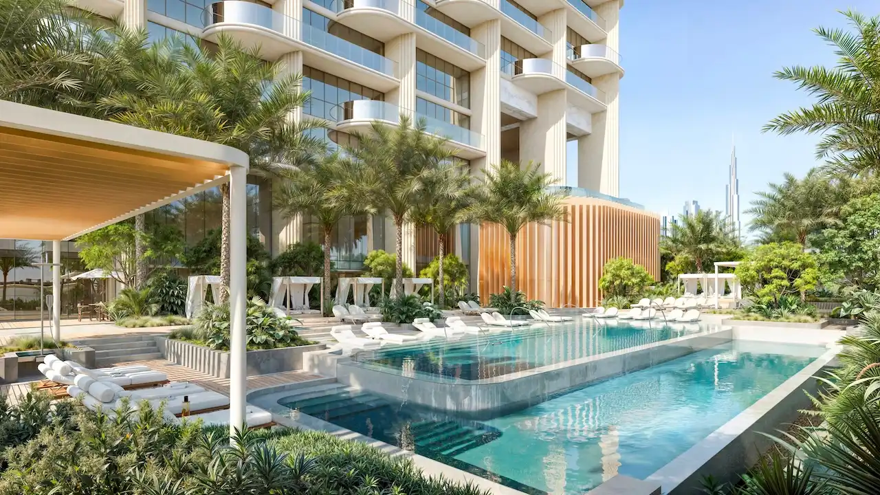 Resort-style podium swimming pool at Atelis at d3 surrounded by palm gardens, cabanas, and contemporary residential architecture in Dubai Design District. Presented by Tohid Fetrat.