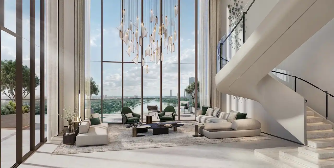 Double-height sky villa living room at Atelis at d3 featuring floor-to-ceiling windows, sculptural staircase, designer chandelier, and panoramic views over Dubai Design District. Presented by Tohid Fetrat.
