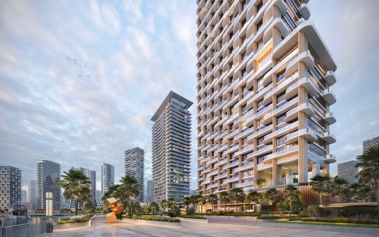Waterfront exterior view of Atelis at d3 featuring a sculpted residential tower with curved balconies, landscaped promenade, palm-lined walkways, and contemporary architecture in Dubai Design District. Presented by Tohid Fetrat.