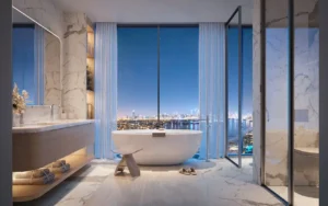 Penthouse master bathroom at Bella at Passo by Beyond featuring a freestanding bathtub, floor-to-ceiling windows, marble finishes, refined contemporary design, and panoramic night views over Palm Jumeirah and the Dubai skyline, Presented by Tohid Fetrat