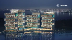 Chelsea Residences by DAMAC illuminated waterfront towers at night, showcasing stepped contemporary architecture and panoramic Gulf views across Dubai’s skyline. Presented by Tohid Fetrat.