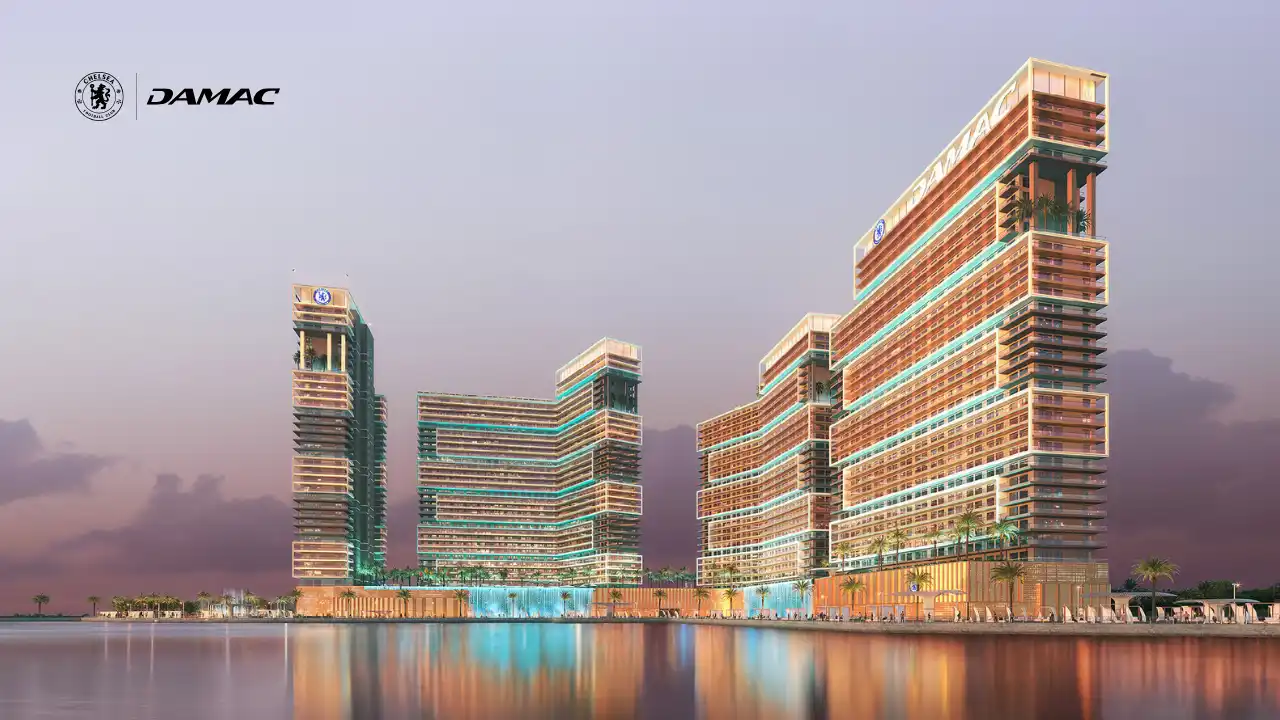 Chelsea Residences by DAMAC waterfront towers featuring stepped contemporary architecture, illuminated façades, and panoramic Gulf views along Dubai’s coastline. Presented by Tohid Fetrat.