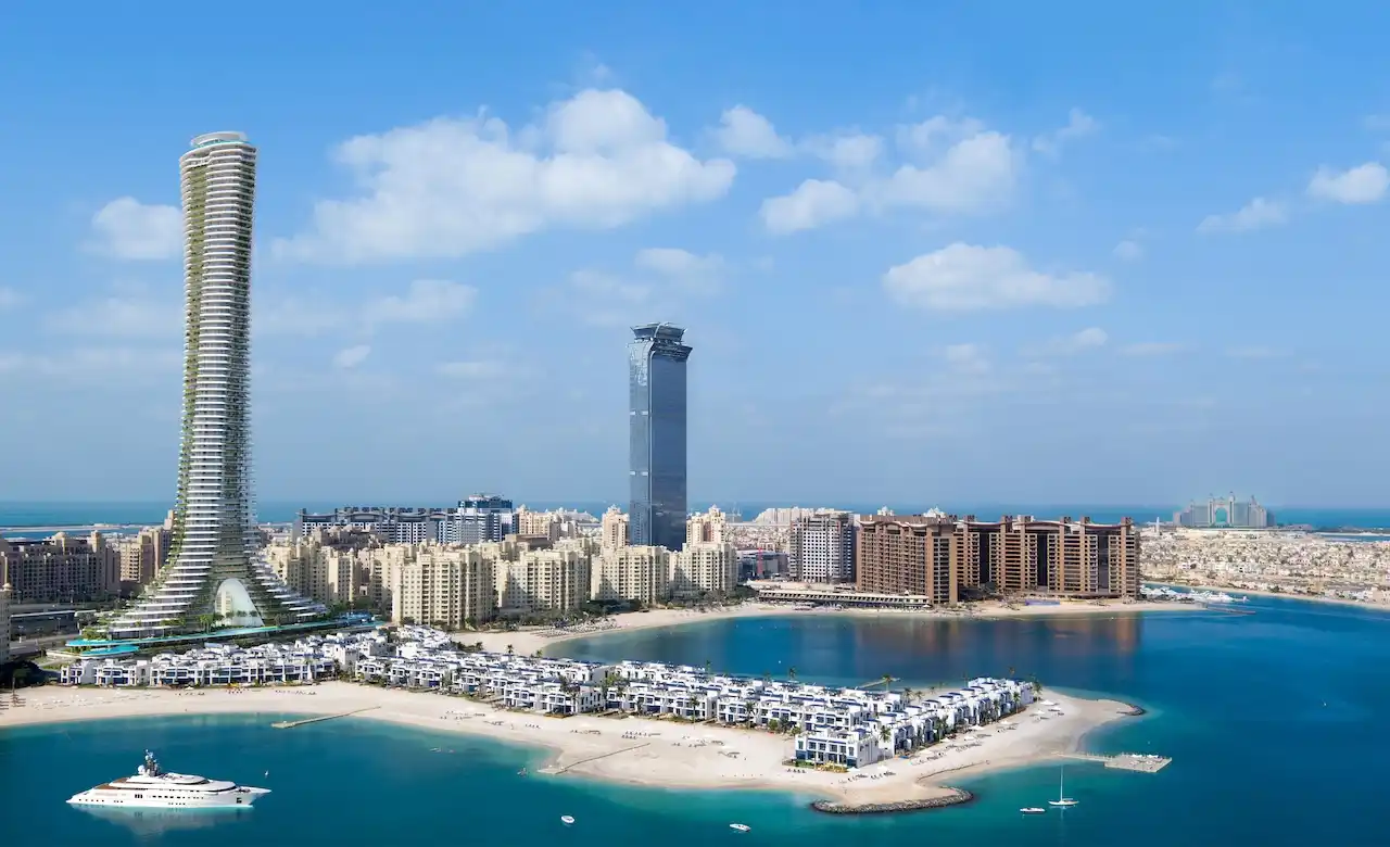 Aerial coastal view of COMO Residences tower on Palm Jumeirah, highlighting its iconic slender architecture, beachfront villas, turquoise Gulf waters, marina setting, and surrounding Dubai skyline. Presented by Tohid Fetrat.