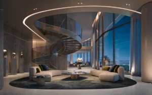 Iconic double-height living room at COMO Residences on Palm Jumeirah featuring a sculptural spiral staircase, curved floor-to-ceiling glass, bespoke lounge seating, and refined ambient lighting with panoramic Gulf views. Presented by Tohid Fetrat.