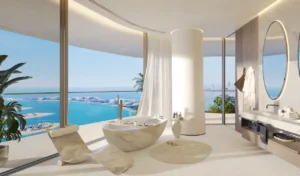 Luxury bathroom interior at COMO Residences on Palm Jumeirah featuring a sculptural freestanding marble bathtub, floor-to-ceiling glass, refined finishes, and panoramic daytime views of the Gulf and Dubai skyline. Presented by Tohid Fetrat.