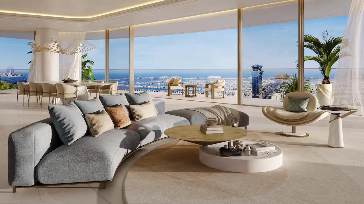Luxury living and dining area at COMO Residences on Palm Jumeirah featuring curved designer sofa seating, elegant dining space, bespoke furniture, floor-to-ceiling windows, and panoramic Gulf and Dubai skyline views. Presented by Tohid Fetrat.