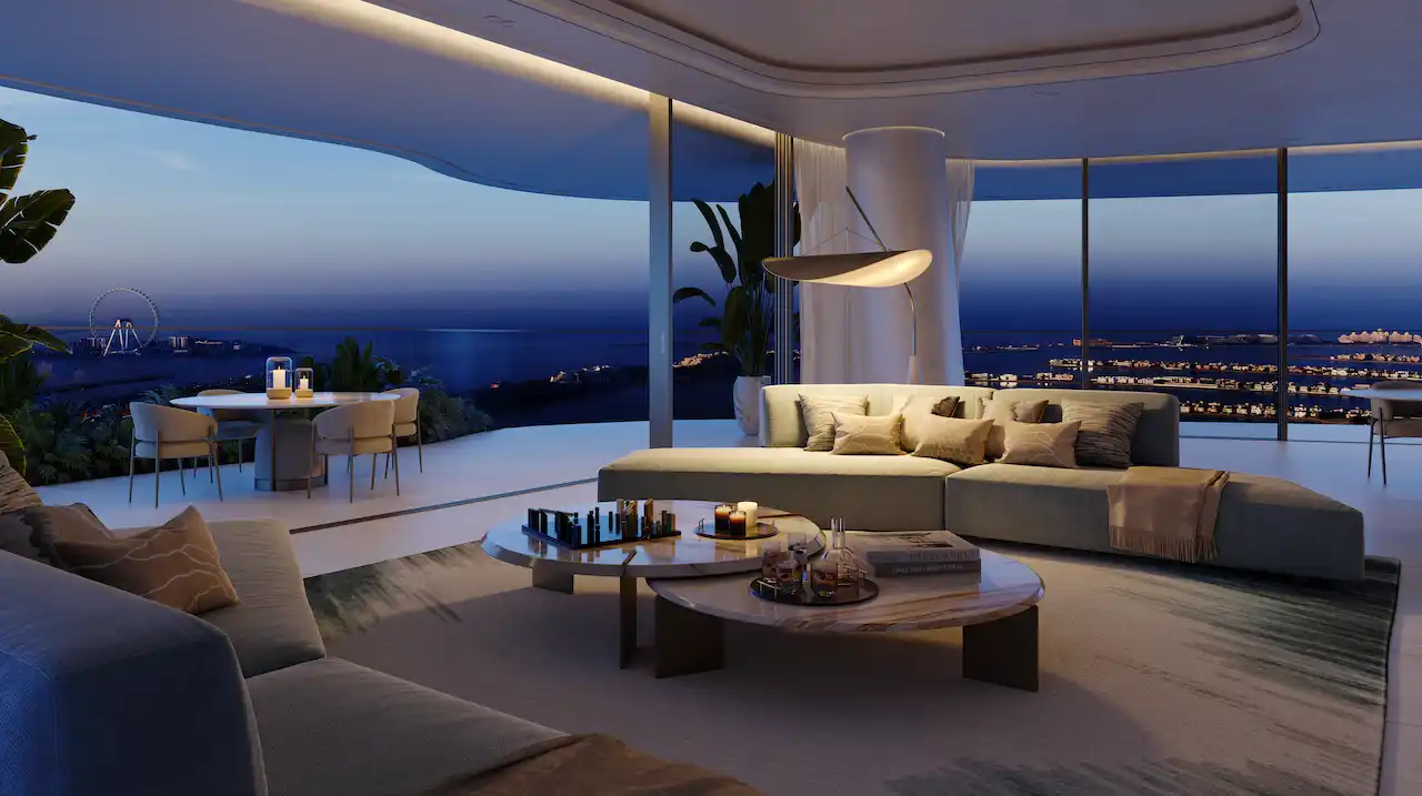 Luxury night-time living area at COMO Residences on Palm Jumeirah featuring designer sofa seating, ambient lighting, bespoke furniture, floor-to-ceiling windows, and panoramic Gulf and Dubai skyline views after sunset. Presented by Tohid Fetrat.
